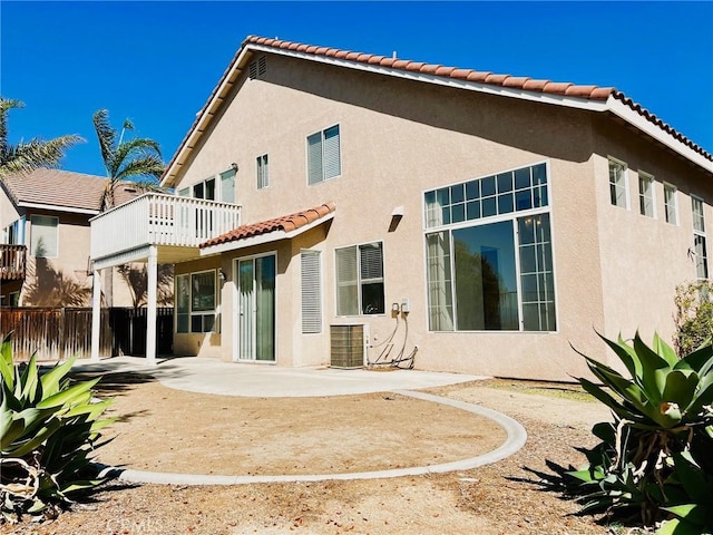 back of property with fence, central AC, stucco siding, a balcony, and a patio area