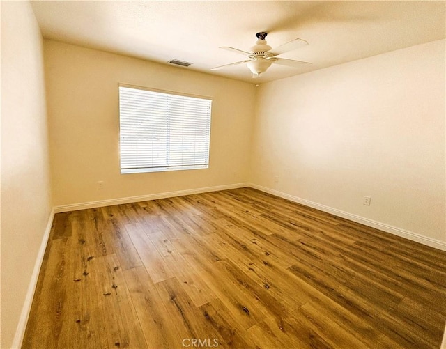 spare room with visible vents, baseboards, a ceiling fan, and wood finished floors