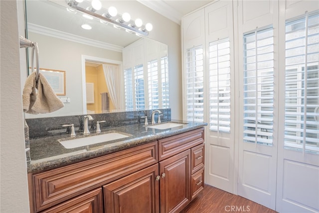 full bathroom with crown molding, plenty of natural light, wood finished floors, and a sink