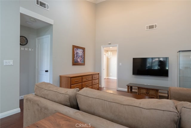 living room with visible vents, baseboards, dark wood-type flooring, and a high ceiling