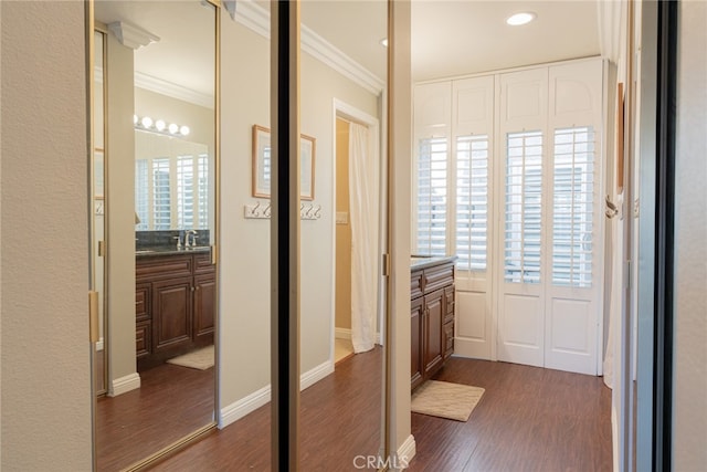 bathroom featuring vanity, crown molding, wood finished floors, and baseboards