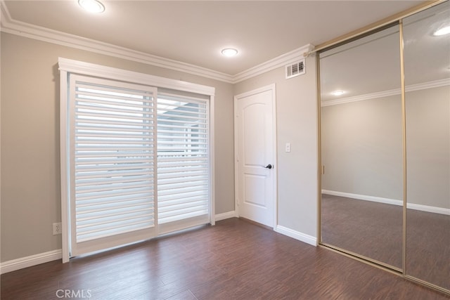 unfurnished bedroom with visible vents, crown molding, baseboards, dark wood-type flooring, and a closet