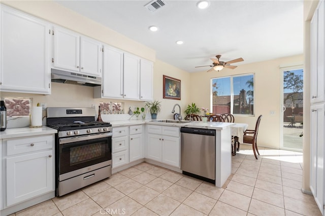 kitchen with visible vents, under cabinet range hood, a peninsula, white cabinets, and stainless steel appliances