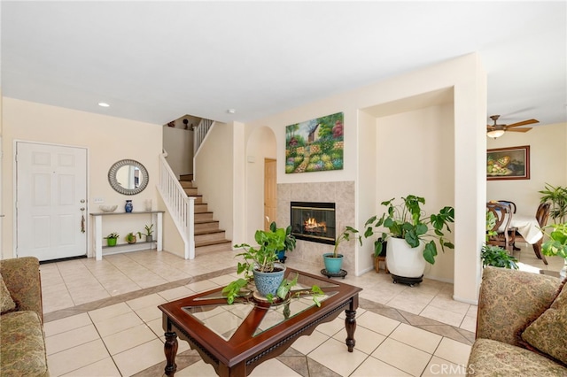 living room with stairway, baseboards, light tile patterned flooring, and a tiled fireplace