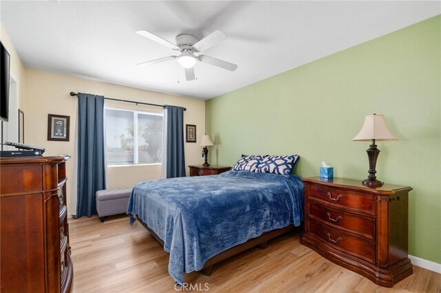 bedroom with ceiling fan, baseboards, and light wood-style floors