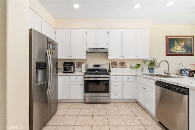 kitchen featuring under cabinet range hood, a sink, appliances with stainless steel finishes, white cabinets, and light tile patterned flooring