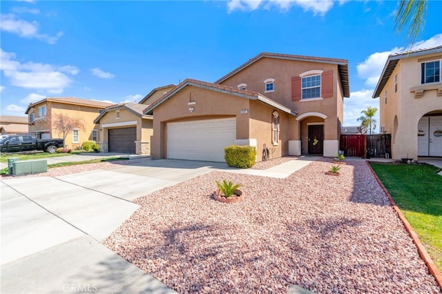 mediterranean / spanish house featuring stucco siding, an attached garage, driveway, and fence