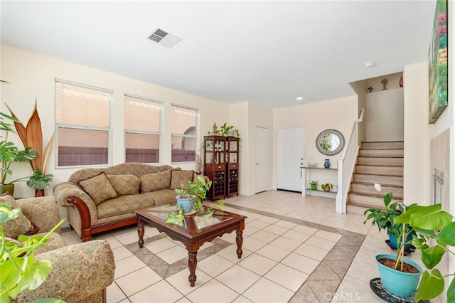 living area featuring light tile patterned floors, visible vents, and stairs