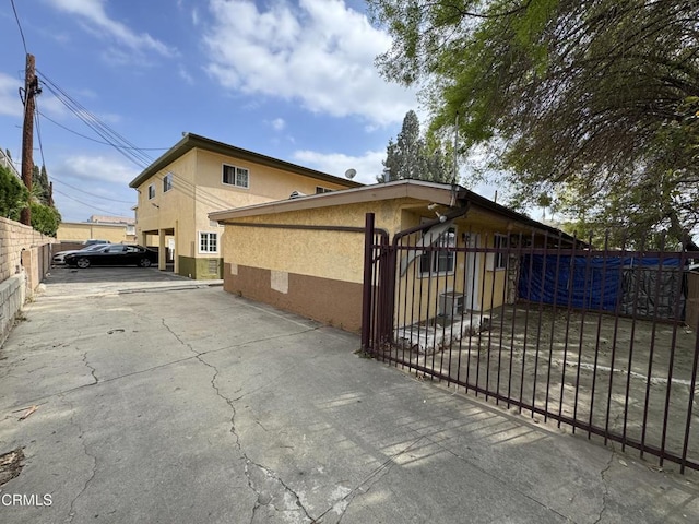 view of side of home featuring stucco siding and fence