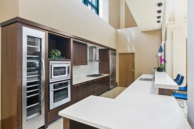 kitchen featuring dark brown cabinets, appliances with stainless steel finishes, modern cabinets, and wall chimney range hood