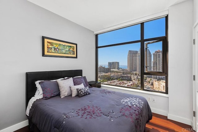 bedroom with baseboards, a view of city, and wood finished floors