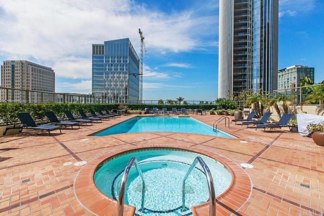 community pool with a city view, a community hot tub, and a patio area