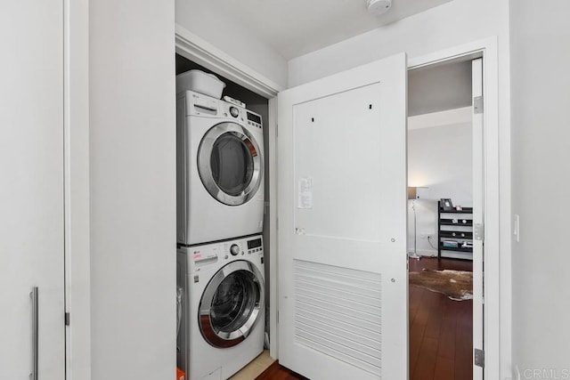 washroom with stacked washer and clothes dryer, wood finished floors, and laundry area