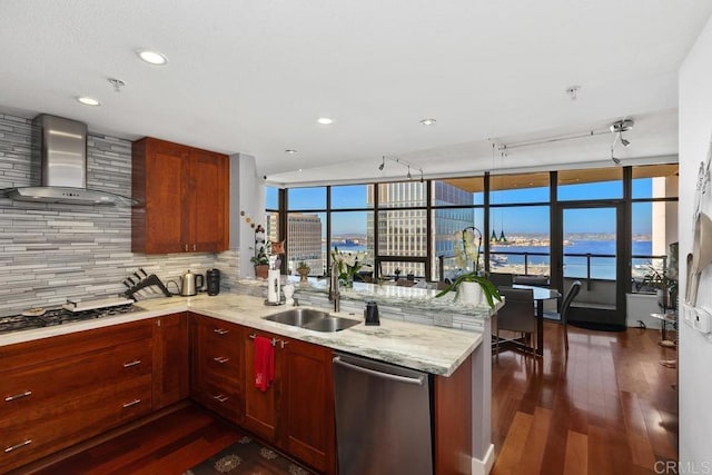 kitchen featuring wall chimney range hood, dark wood finished floors, dishwasher, a peninsula, and gas cooktop