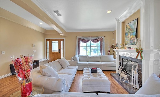 living room featuring visible vents, ornamental molding, wood finished floors, a fireplace, and baseboards