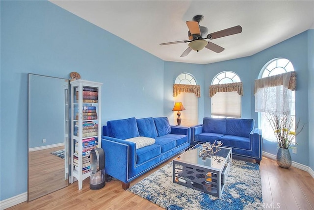 living room with ceiling fan, baseboards, and wood finished floors