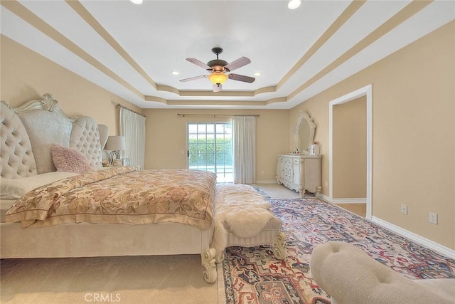 bedroom featuring access to outside, a tray ceiling, recessed lighting, baseboards, and ceiling fan