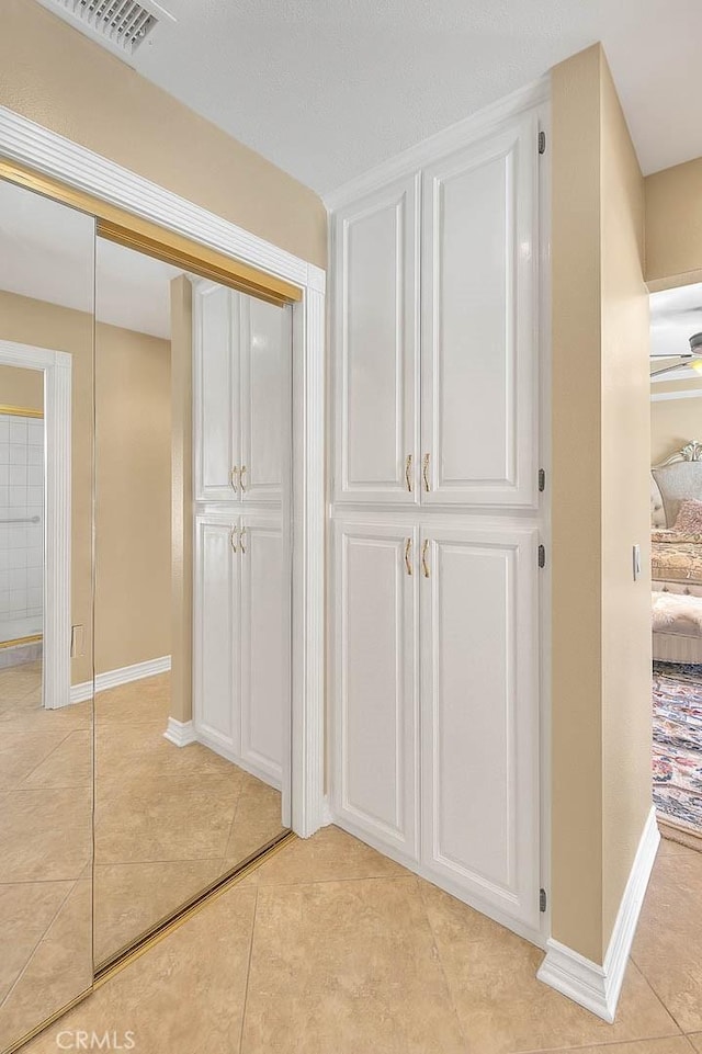 hallway featuring light tile patterned flooring, baseboards, and visible vents