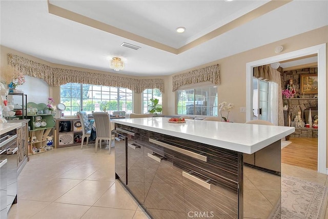 kitchen featuring light tile patterned floors, a raised ceiling, and light countertops