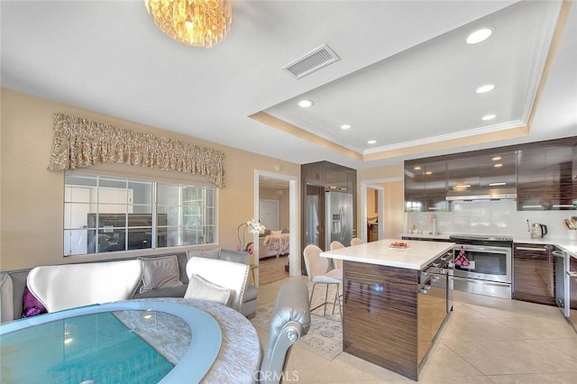 kitchen featuring a tray ceiling, extractor fan, visible vents, and stainless steel appliances