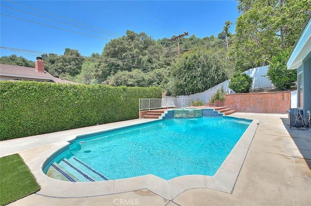 view of pool featuring a patio, a fenced backyard, and a pool with connected hot tub