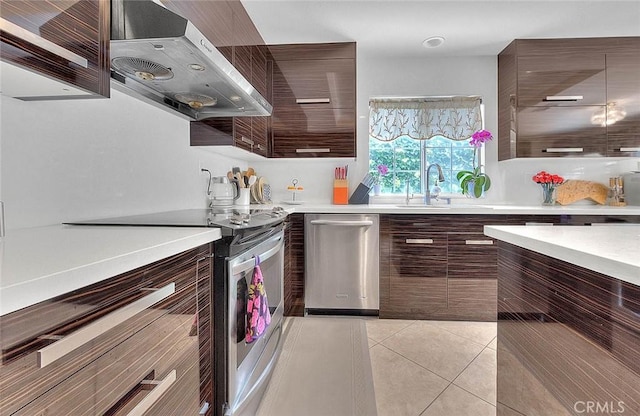 kitchen featuring under cabinet range hood, light countertops, light tile patterned floors, stainless steel appliances, and modern cabinets