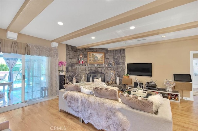 living area featuring visible vents, light wood finished floors, beam ceiling, recessed lighting, and a stone fireplace