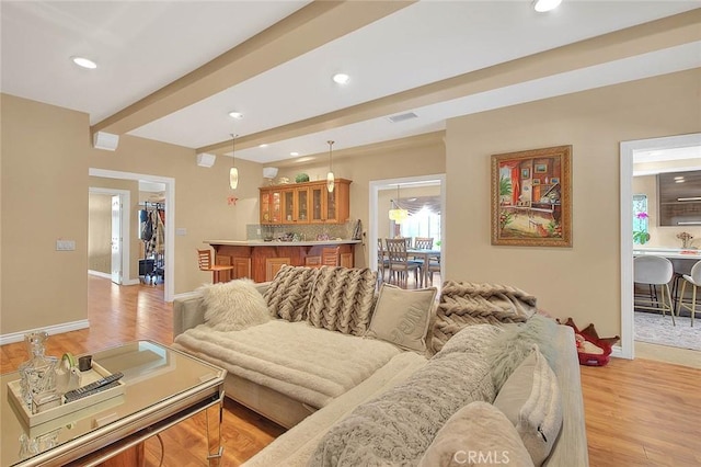 living room with visible vents, baseboards, beam ceiling, light wood-style flooring, and recessed lighting