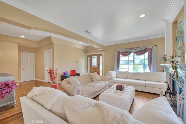 living area featuring visible vents, baseboards, ornamental molding, recessed lighting, and wood finished floors