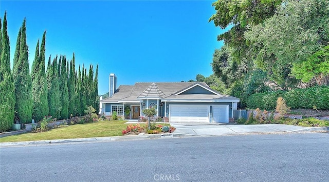 view of front of house with a front yard, fence, driveway, an attached garage, and a chimney