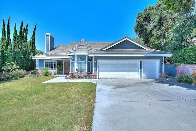 ranch-style home with a tiled roof, concrete driveway, a front yard, a chimney, and an attached garage