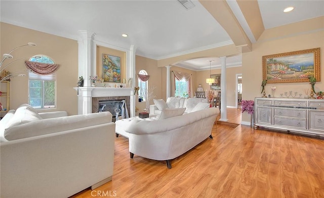 living room featuring light wood-style floors, a healthy amount of sunlight, a fireplace, and ornate columns