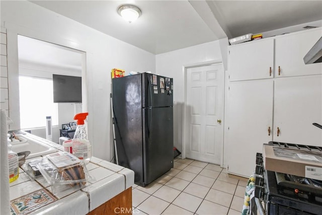 kitchen with light tile patterned floors, white cabinetry, and freestanding refrigerator