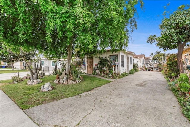 view of front of house featuring a residential view, stucco siding, concrete driveway, and a front lawn