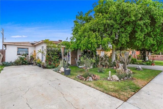 obstructed view of property with stucco siding, solar panels, concrete driveway, and a front lawn