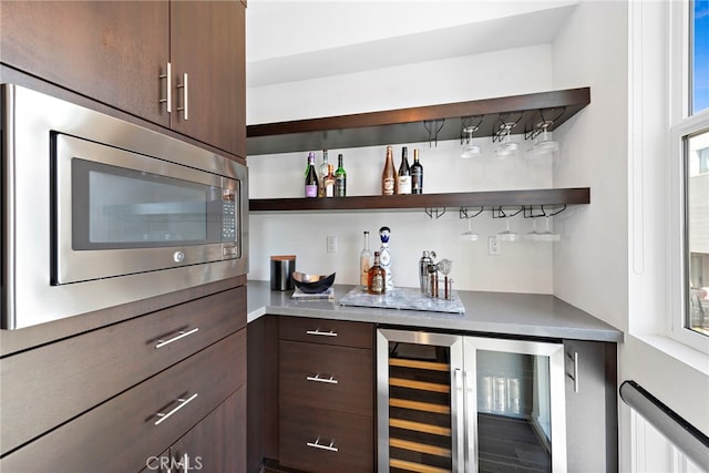 bar featuring a bar, stainless steel microwave, and beverage cooler