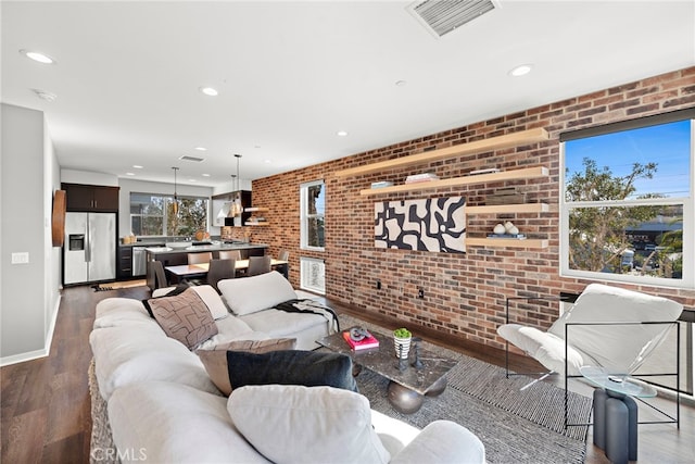 living area featuring visible vents, recessed lighting, brick wall, and wood finished floors