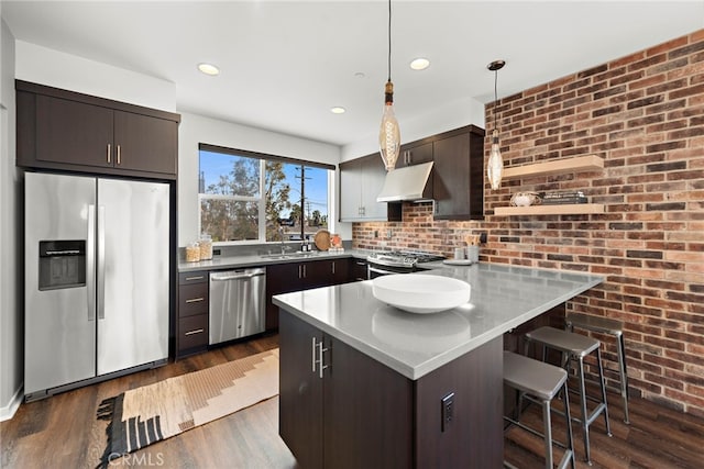 kitchen with ventilation hood, appliances with stainless steel finishes, a peninsula, and dark wood finished floors