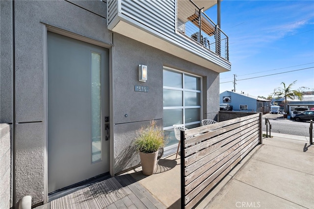 entrance to property with stucco siding and a balcony