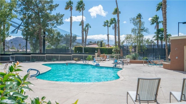 community pool featuring a patio area, a mountain view, and fence