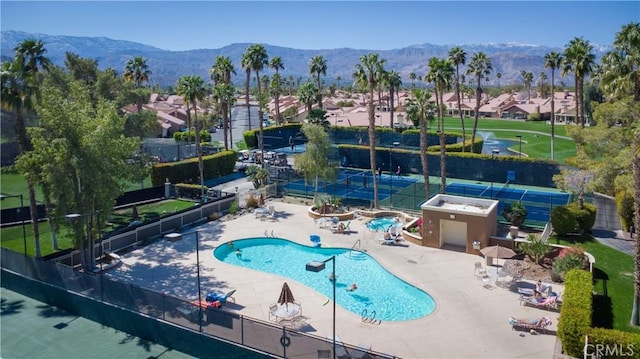 community pool featuring a patio area, a residential view, a mountain view, and fence