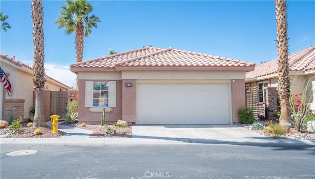 mediterranean / spanish house featuring fence, driveway, an attached garage, stucco siding, and a tile roof