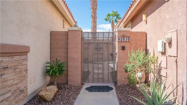 exterior space featuring stucco siding, a tile roof, and a gate