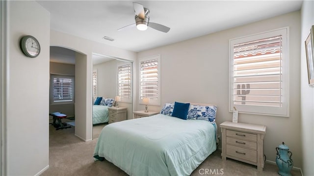 bedroom with visible vents, arched walkways, ceiling fan, and carpet flooring