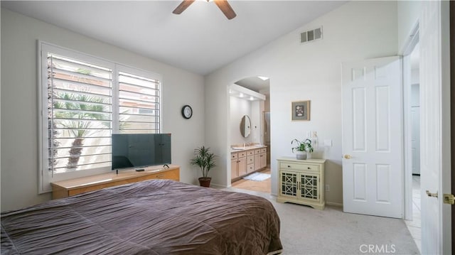 bedroom featuring visible vents, arched walkways, vaulted ceiling, light carpet, and connected bathroom