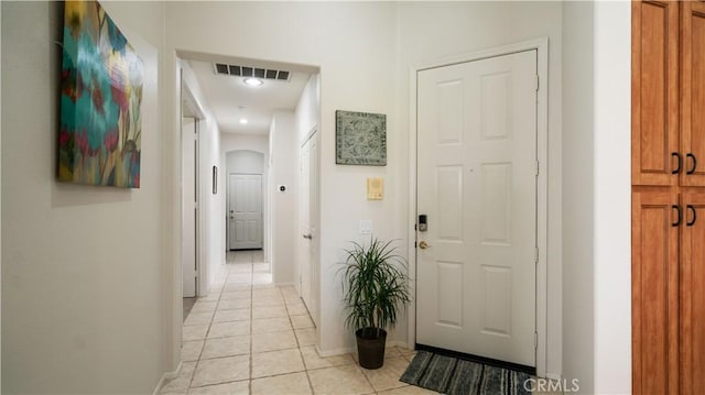 hall with arched walkways, visible vents, baseboards, and light tile patterned floors