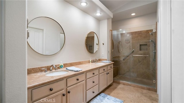 bathroom with a shower stall, double vanity, and a sink
