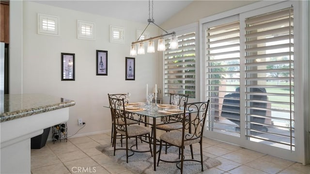 dining area with lofted ceiling, light tile patterned floors, and baseboards