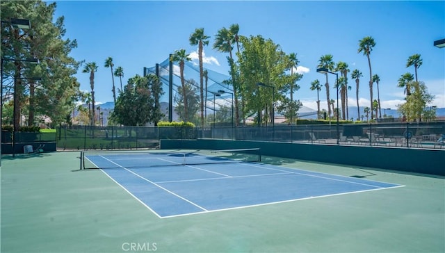 view of tennis court featuring community basketball court and fence