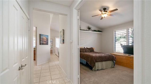 bedroom featuring vaulted ceiling, light tile patterned flooring, light colored carpet, and ceiling fan